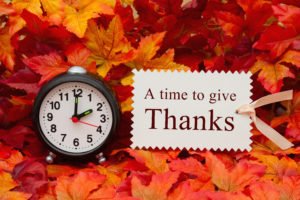 Time to give thanks message Some fall leaves and black and white alarm clock and beige gift tag with text A Time to give thanks